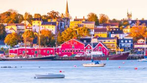 An image of Lunenberg, Nova Scotia from the water. A large red building is on the on the water, with a town behind