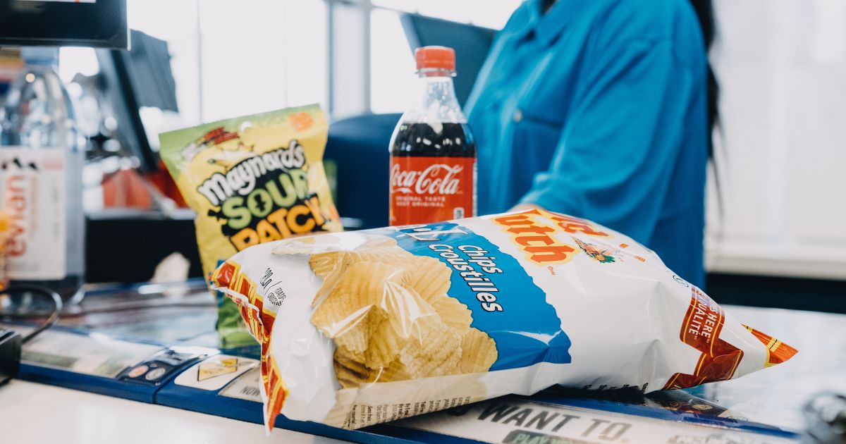 Image of bag of chips, sour candy and a bottle of pop being purchased as a cash register